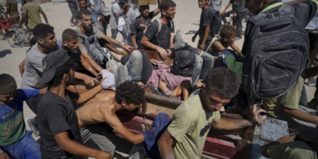 Palestinos son trasladados tras resultar heridos al intentar alcanzar camiones con ayuda humanitaria en Gaza, ayer.