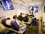 Personal vestido como asistente de vuelo sirve comidas a los clientes de First Airlines, que brinda experiencias de vuelo de realidad virtual.