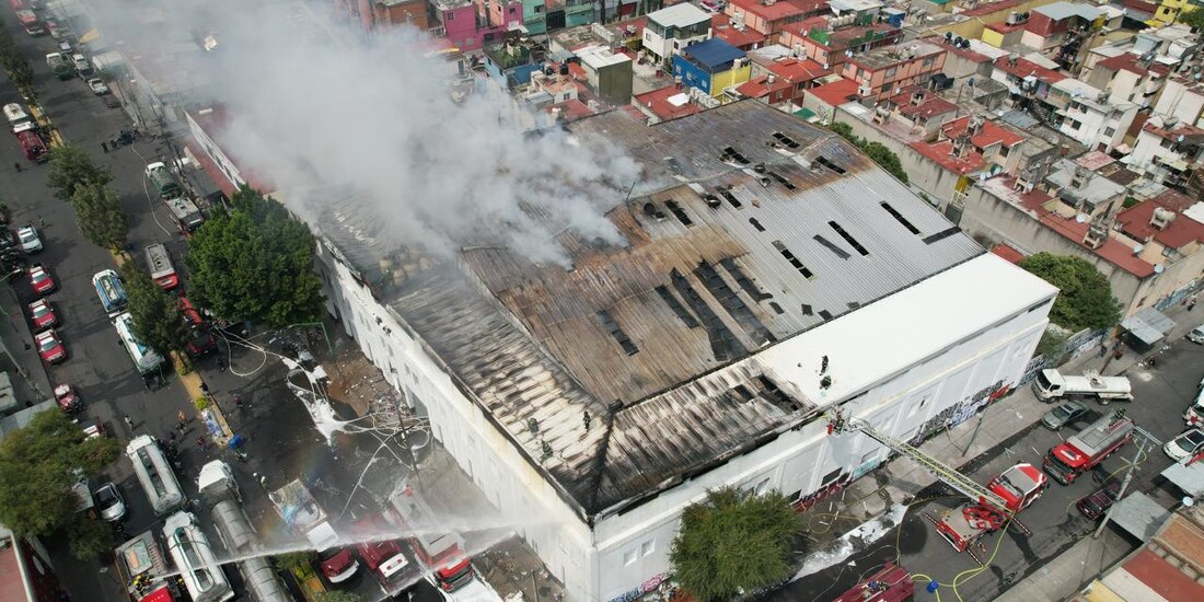 Bomberos trabajan en sofocar el fuego de la bodega afectada, ayer.