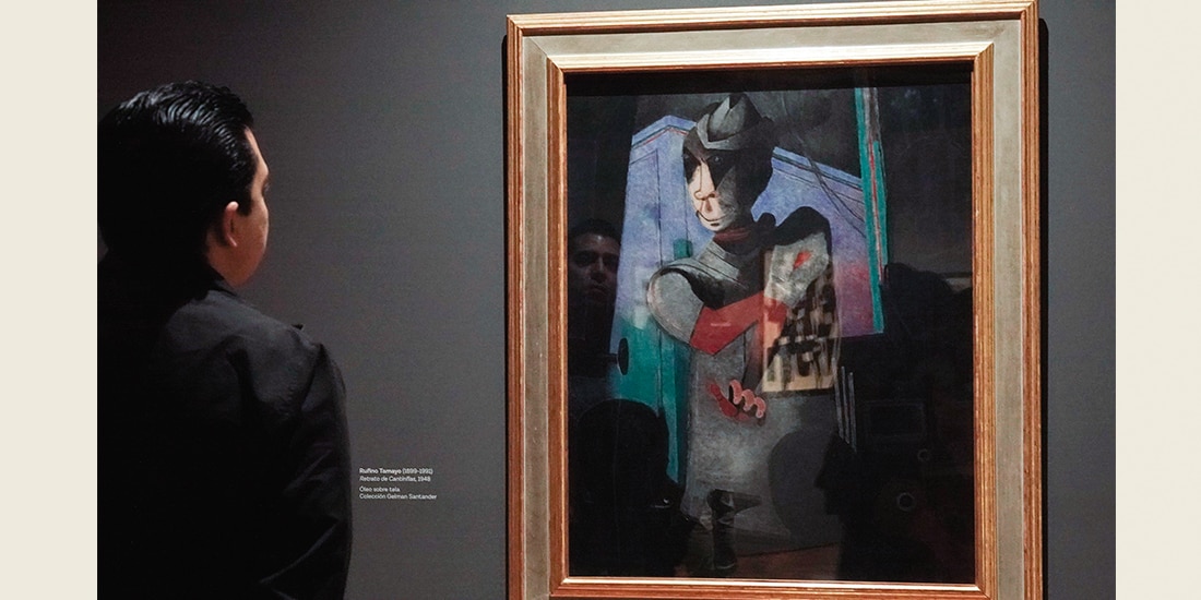 Un hombre admira una pintura de Cantinflas de Rufino Tamayo