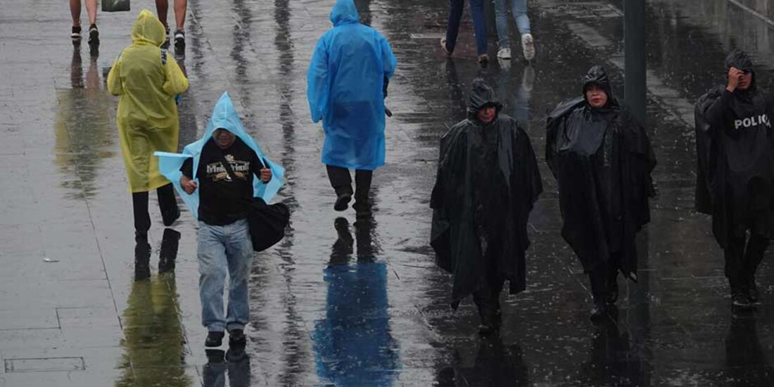 Perdonas que caminan por la calle, protegiéndose con plásticos de la lluvia