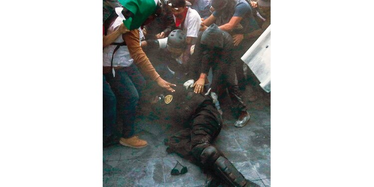 Momento en que un policía es agredido por encapuchados, el jueves.