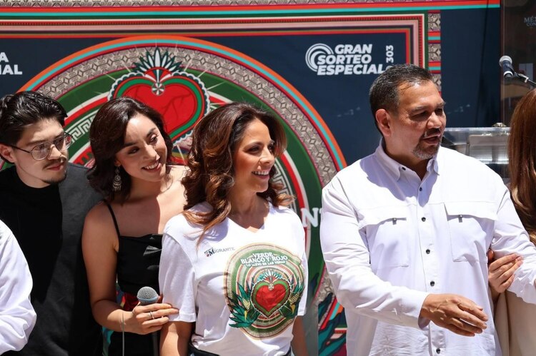 Olivia Salomón y Cruz Pérez Cuéllar presentan el billete del sorteo en el Puente Internacional Paso del Norte.