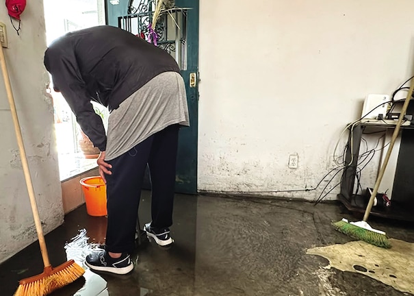Un hombre recolecta el líquido dentro de su vivienda en una cubeta, ayer.