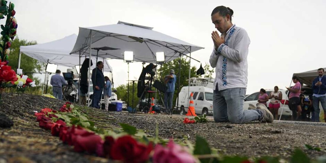 Una persona realiza una oración en el lugar donde fueron encontrados los migrantes en la caja de un tráiler