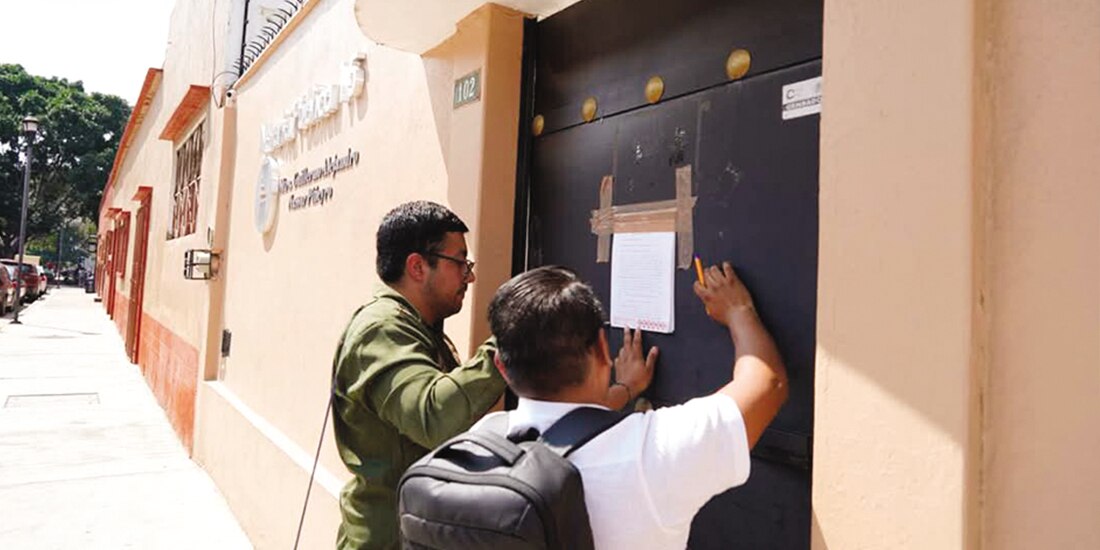 Personal de la Consejería Jurídica de Oaxaca coloca sellos de advertencia sobre la cancelación de la notaría, el martes.