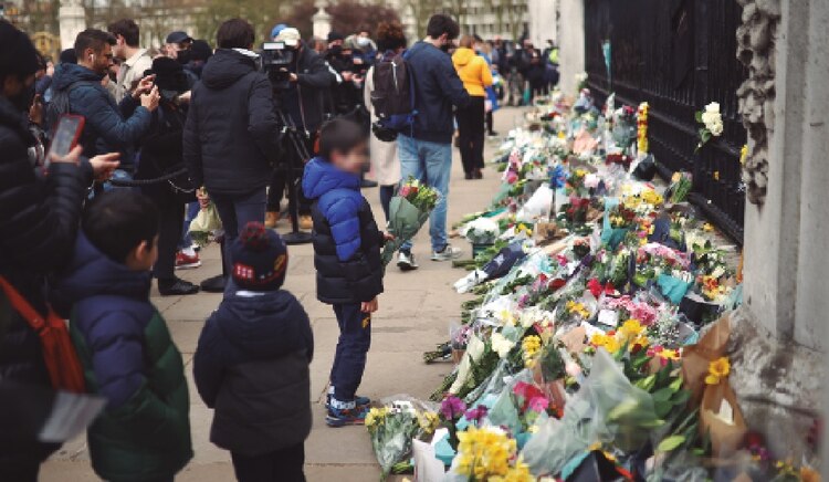 Un niño deposita flores afuera de la residencia oficial de la reina, en Londres, ayer.