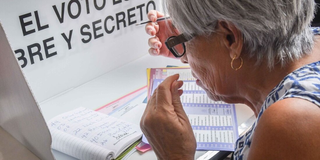 Una adulto mayor se respalda con un acordeón escrito por ella misma para decidir y emitir su voto en la boleta adecuada en las elecciones del Poder Judicial.