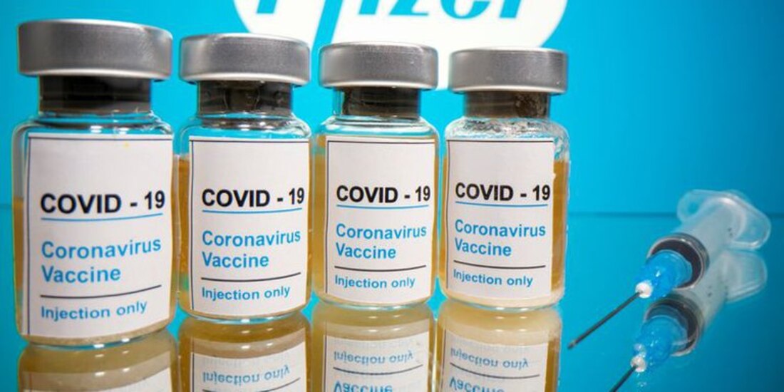Fotografía tomada el 31 de octubre de 2020 en la que se ven frascos con etiquetas que dicen "COVID-19/Vacuna contra el coronavirus/Solo inyección" y una jeringa médica frente al logotipo de Pfizer.