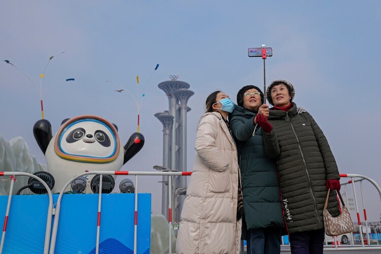 Mujeres en China posan para una foto ante la mascota de los Juegos Olímpicos de Invierno de Beijing, ayer.