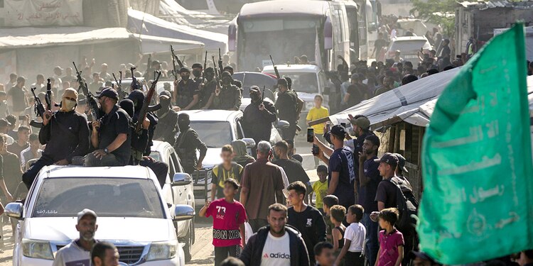 Milicianos armados de Hamas escoltan un autobús con prisioneros liberados que llegan a la Franja de Gaza, el lunes 13 de octubre.