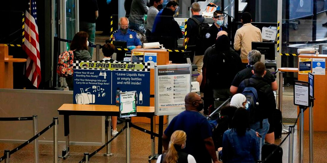 Los viajeros hacen cola en una fila de seguridad limitada por el distanciamiento social en el Aeropuerto Internacional de Seattle-Tacoma en SeaTac, Washington.