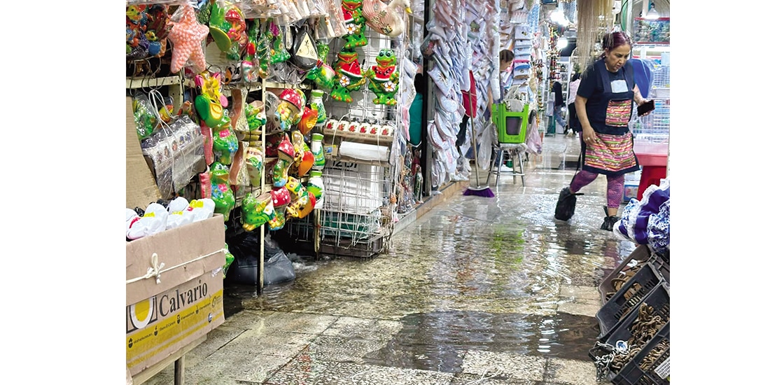 Una vendedora usa bolsas en los pies por la inundación, ayer.