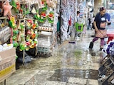 Una vendedora usa bolsas en los pies por la inundación, ayer.