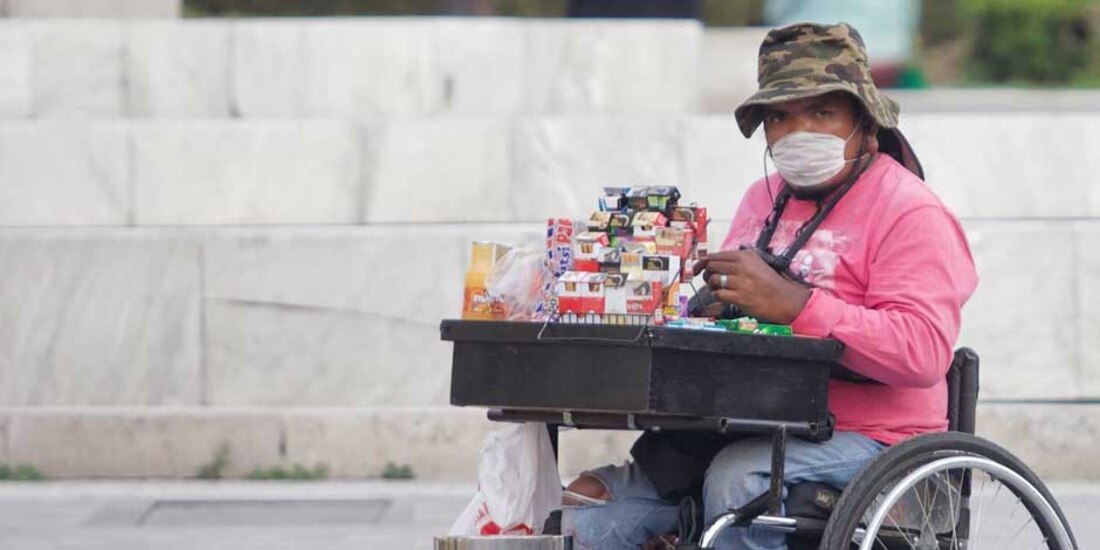 Una mujer en silla de ruedas vende cigarros y golosinas. Utiliza un cubrebocas para protegerse del COVID-19