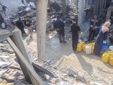 Palestinos colectan agua en una vivienda destrozada por un ataque israelí, ayer, en Jabalia.