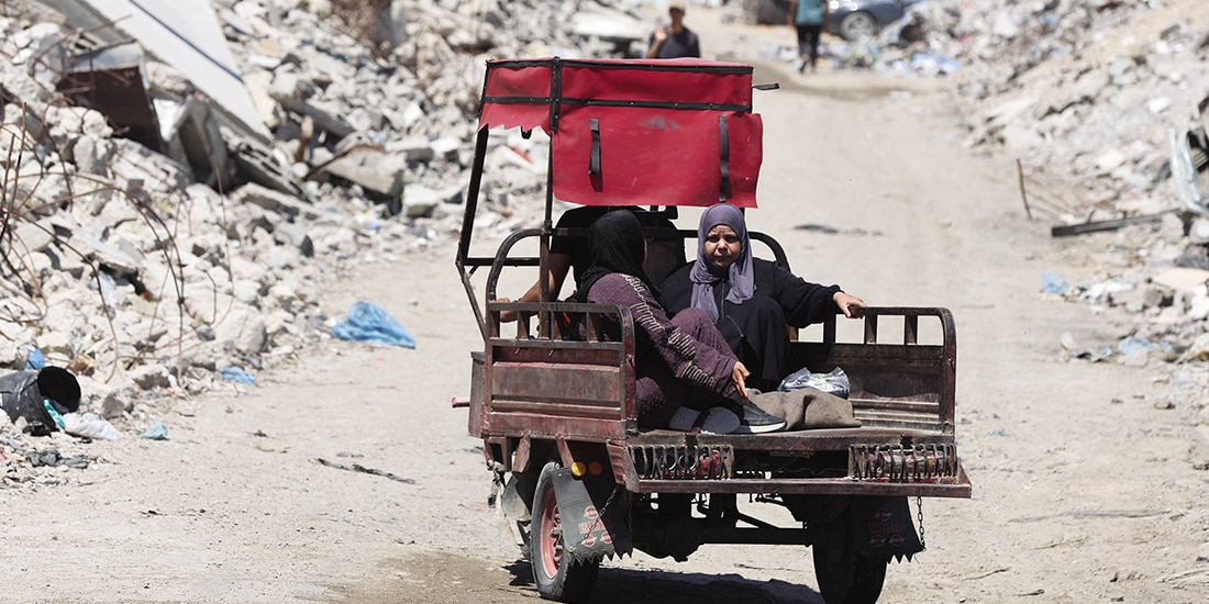Palestinos pasan por escombros de edificios en la ciudad de Gaza, ayer.
