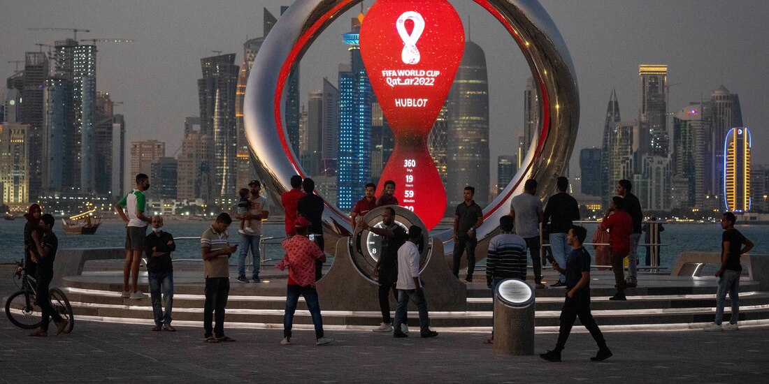 Gente reunida alrededor del reloj de la cuenta regresiva oficial que muestra el tiempo restante para el inicio del Mundial Qatar 2022.