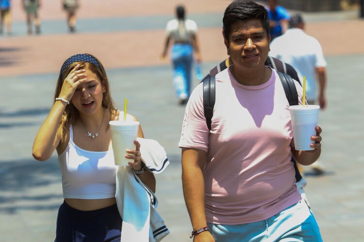 Las personas intentan mitigar el calor utilizando sombrillas para cubrirse. Imagen de archivo.