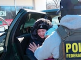 UNA MUJER con un niño sube al vehículo de un agente de inmigración en Minneapolis, ayer.