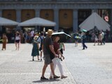Una pareja se refugia del sol bajo una sombrilla en la Plaza Mayor durante la segunda ola de calor del año en Madrid, España.