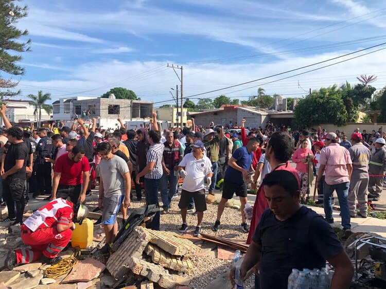 Personas levantan la mano derecha, solicitando silencio 