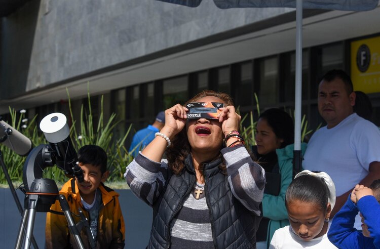 En Toluca, una familia observa el eclipse con lentes especiales.