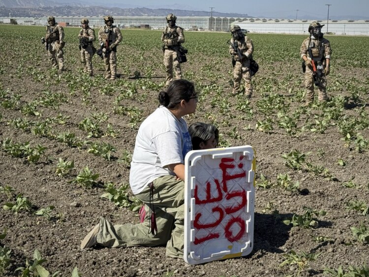 dos migrantes se hincan ante agentes federales, en una redada el pasado 10 de julio, en California.