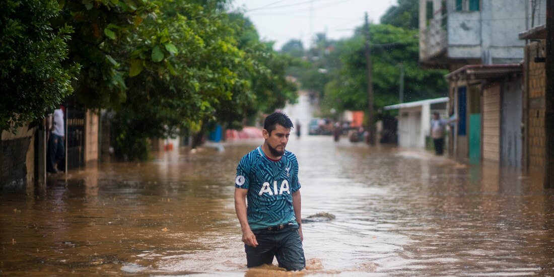 Un hombre camina en una calle inundada en Acayucan, Veracruz.