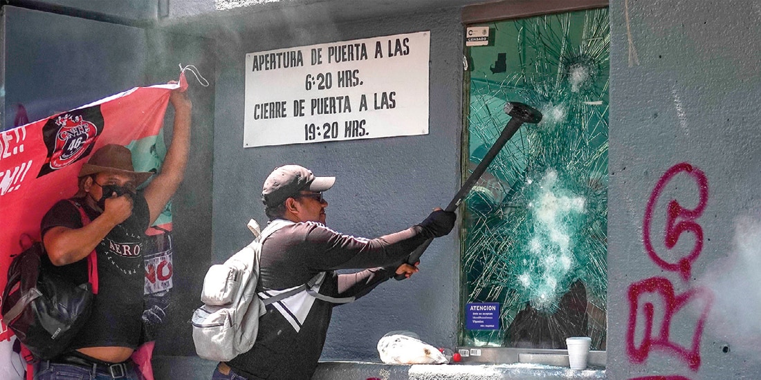 MANIFESTANTES rompen los vidrios de una caseta con un mazo, ayer, en la sede de la colonia Xoco.