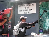 MANIFESTANTES rompen los vidrios de una caseta con un mazo, ayer, en la sede de la colonia Xoco.