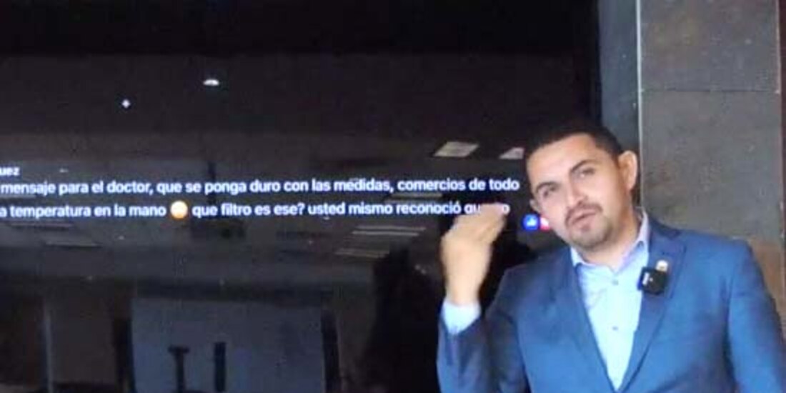 Alonso Pérez, secretario de Salud de Baja California, señala la frente, al recordar que es la manera correcta de medir la temperatura.