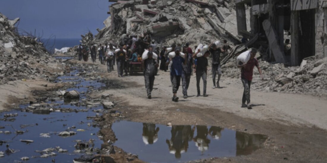 Palestinos cargan sacos de harina de un convoy de ayuda humanitaria que llegó a Gaza, ayer.