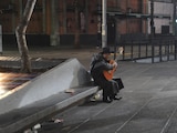 Un hombre toca su guitarra en una banca, en 2020.