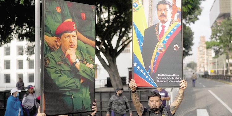 Manifestantes exhiben carteles del presidente Nicolás Maduro (derecha) y de Hugo Chávez en el centro de Caracas, Venezuela, el sábado 3 de enero.