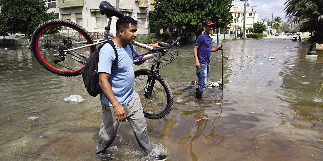 Hombre lleva una bicicleta por una calle inundada en La Habana, ayer.