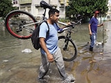 Hombre lleva una bicicleta por una calle inundada en La Habana, ayer.