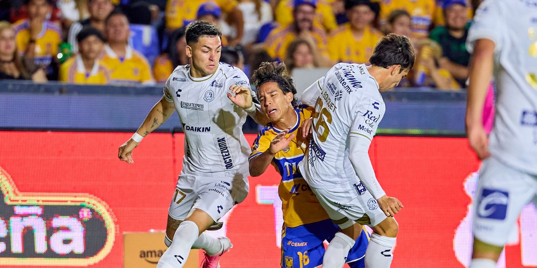 Diego Lainez intenta pasar entre dos jugadores en el duelo entre Tigres y Atlético de San Luis.