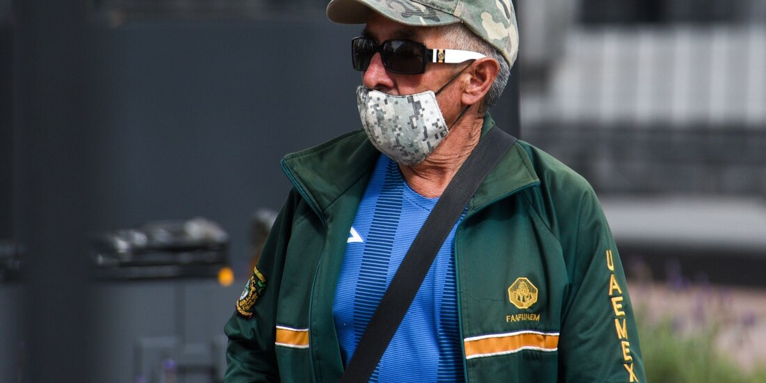 Una hombre camina por la calle, cubriendo sus vía respiratorias con un cubrebocas