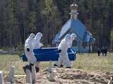 Cavadores de tumbas llevan un ataúd mientras entierran a una víctima de COVID-19 en un cementerio en Kolpino, en San Petersburgo, Rusia, el 10 de mayo de 2020.