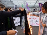 Mujer iraní, entre lágrimas, quema su velo durante una protesta en Suiza.