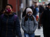 Personas con cubrebocas, chamarras y guantes transitan por el primer cuadro de la ciudad
