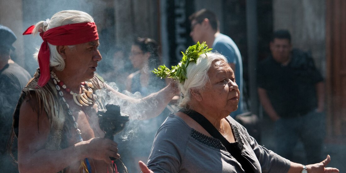 Personas que visitan el zócalo capitalino aprovechan a los curanderos que se encuentran a un costado de la catedral metropolitana para realizarse una limpia.