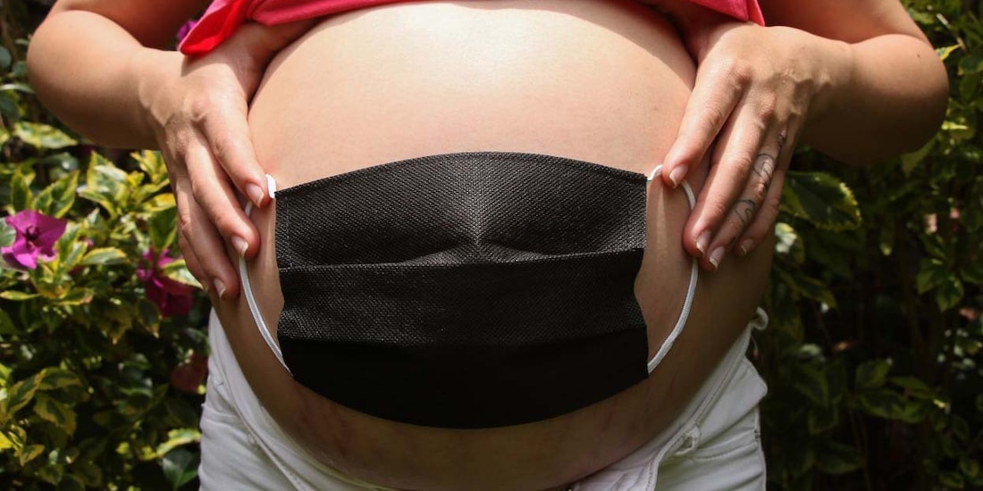 Mujer embarazada se coloca cubrebocas en el vientre como signo de protección para el bebé.