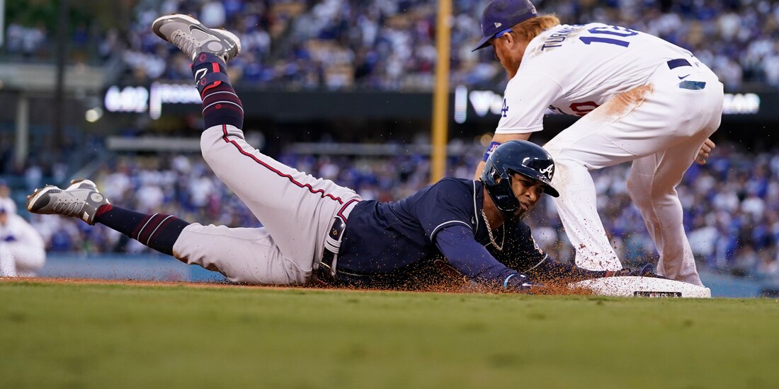 Eddie Rosario, de los Braves, se desliza sobre el tercera base de los Dodgers, Justin Turner.