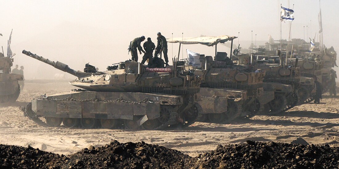 Soldados israelíes se encuentran sobre un tanque estacionado cerca de la frontera entre Israel y Gaza, ayer.