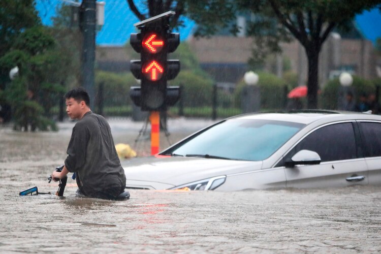 El agua cubre la mitad del cuerpo de un hombre en bicicleta, ayer en Zhengzhou.