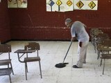 Una persona limpia un salón de clases