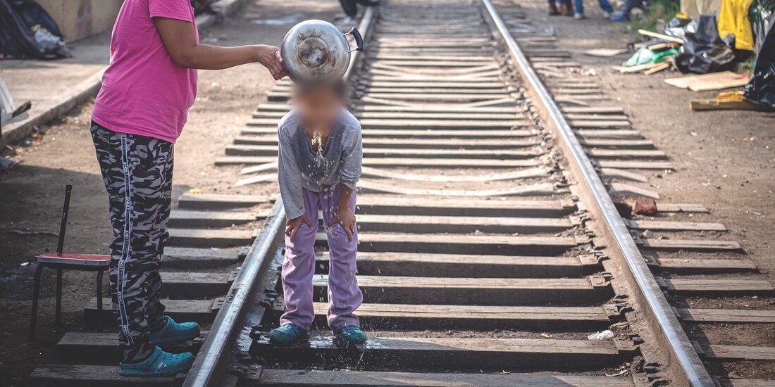 Una mujer baña a su hija en el campamento migrante ubicado en Misterios, en CDMX.
