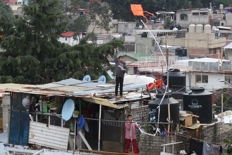 Ante el encierro, dos niños vuelan papalotes en el techo de su casa, en la CDMX.